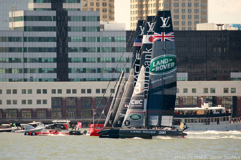 Oracle Team USA, Softbank Team Japan, and Land Rover BAR head down the Hudson River. The red and black catamaran powerboat keeping pace with them, at left, is the on-course television camera boat.